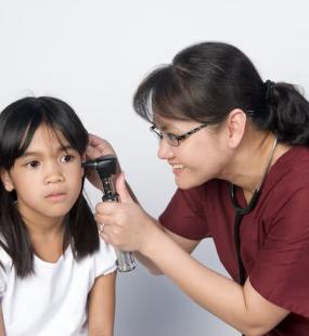 Doctor taking temperature in young girl's ear