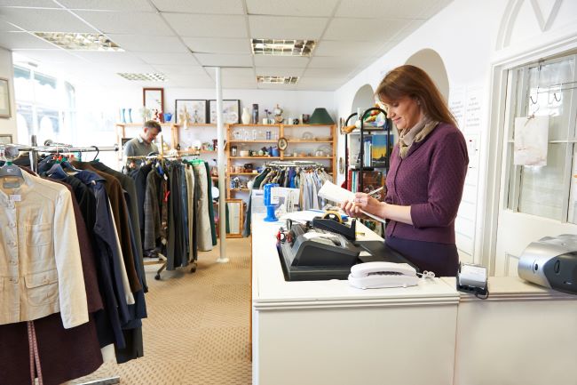 Woman writing on notepad at charity shop counter