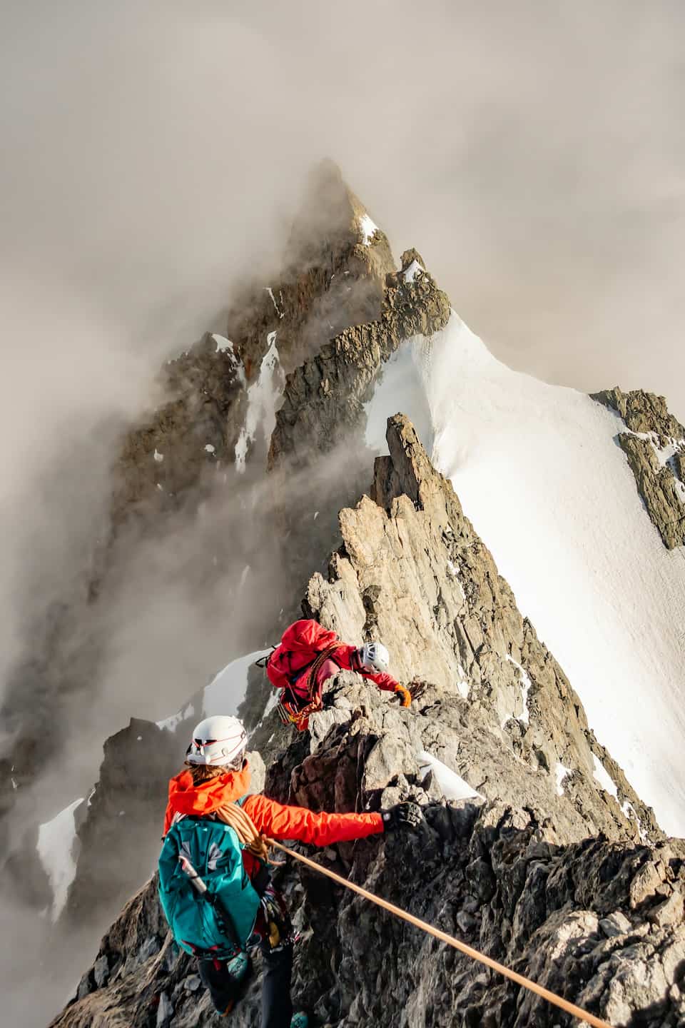 Two people climbing a mountain together