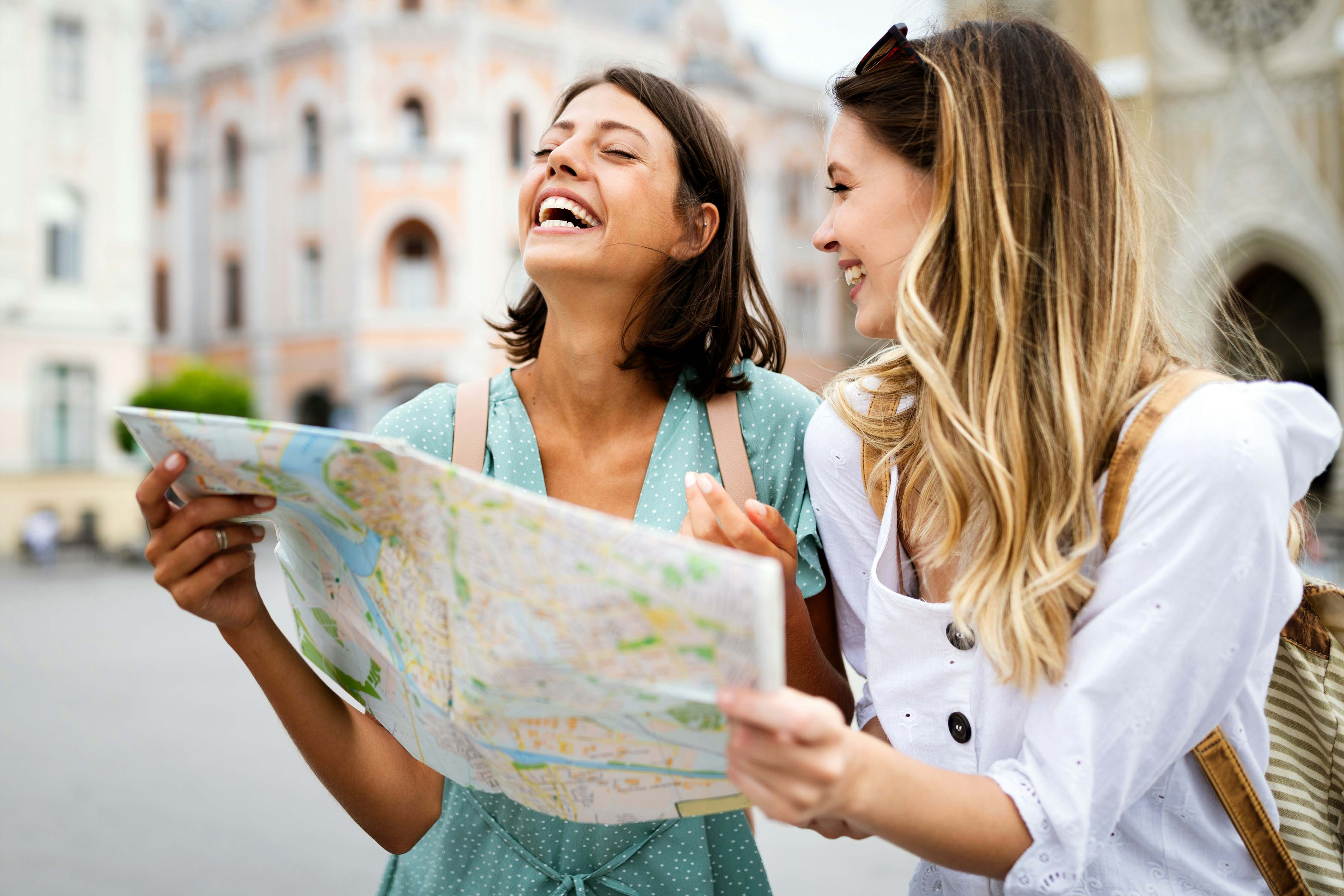 Two people smiling and looking at a map while exploring a city together