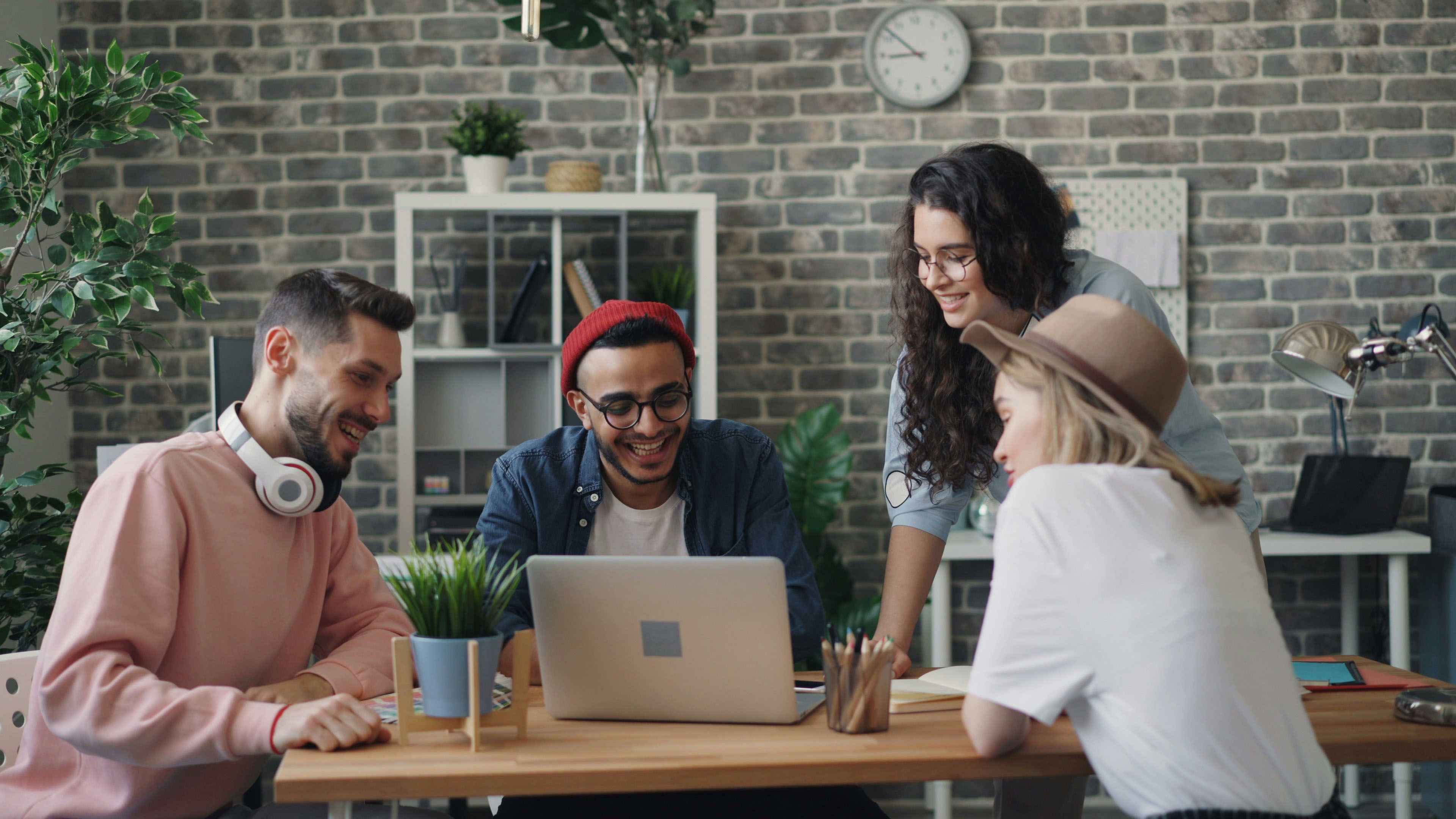 Group of colleagues collaborating around a laptop in an office setting