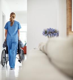 An older couple sit on a bench looking at a view of the sea