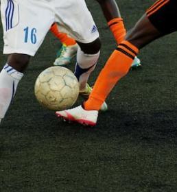 footballers tackling and kicking a ball 