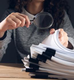 woman holding magnifying glass and documents