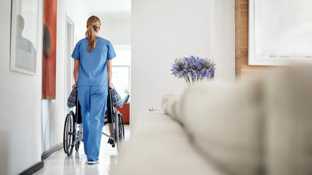 An older couple sit on a bench looking at a view of the sea