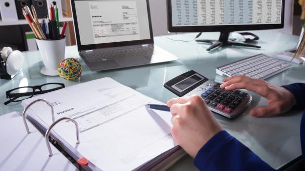 A financial adviser uses a calculator while reading through a folder of data