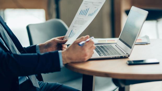 A financial accountant reviews a page of figures while using his laptop