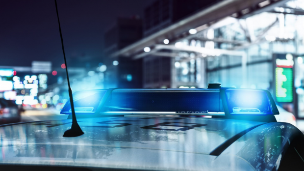 The roof of a police car with flashing blue lights in front of an airport