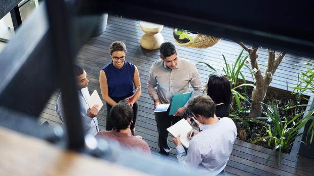 A group fo young workers have a conversation in a hallway