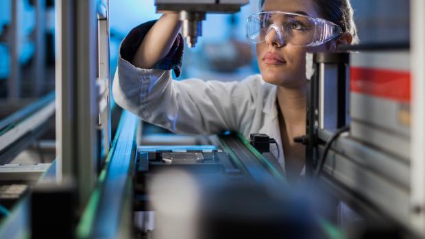 Woman in lab coat working precision manufacturing machine