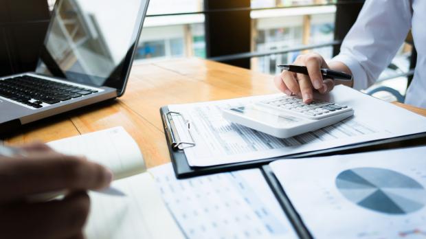 Desk with laptop, papers and hands during meeting