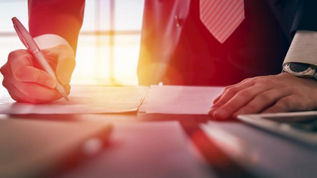 Man in suit writing with a pen