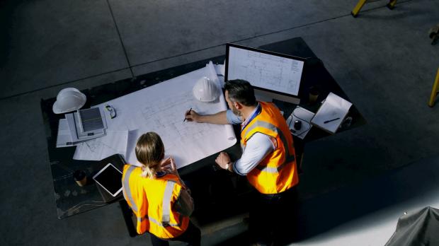 Construction workers look at plans on table