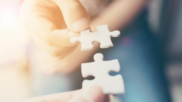 Two people putting puzzle pieces together