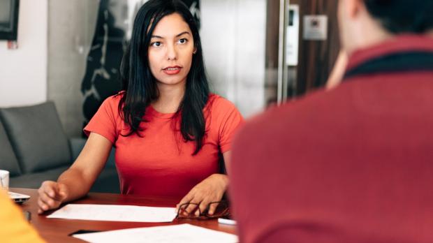 Businesswoman at desk speaking to man