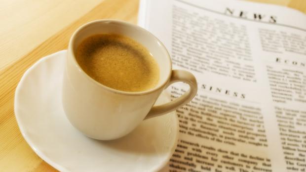 Cup of Coffee next to a news bulletin