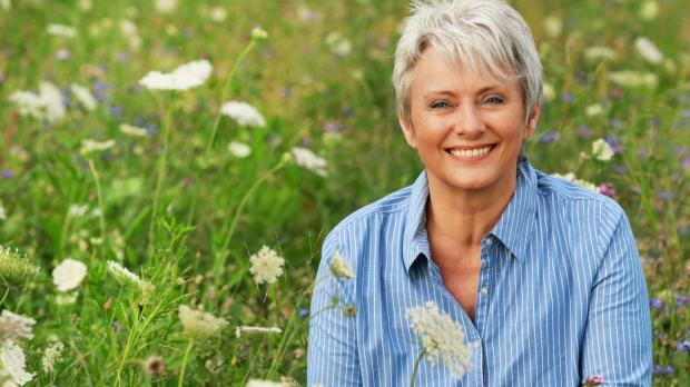Smiling woman sitting in meadow flowers