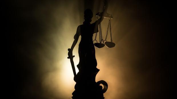 Statue of Lady Justice in the dark, facing towards the light