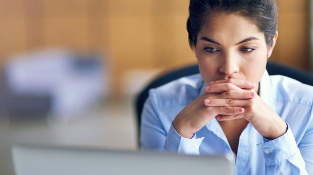 A women sat looking at her work laptop with a concerned expression