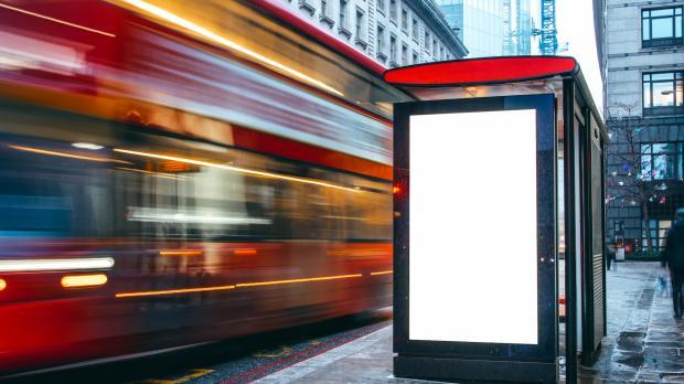Blank advertising hoarding at bus stop with bus whizzing by