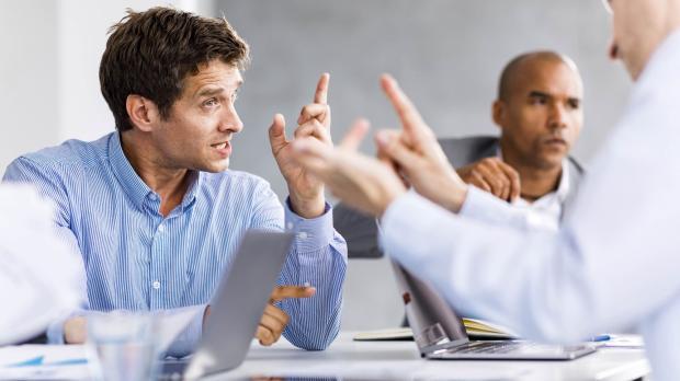Men having heated discussion across a meeting table