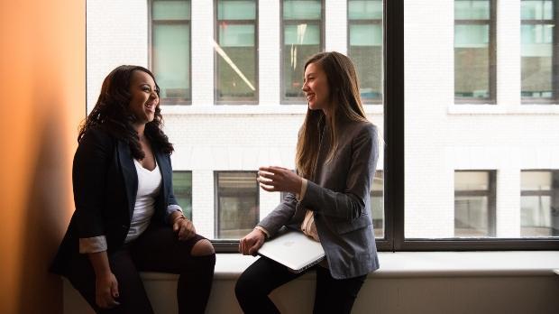 two business people talk by a cityscape window