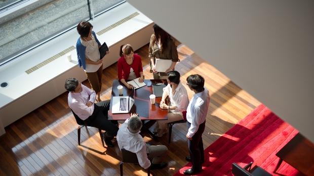 group of business people sit around a work desk 