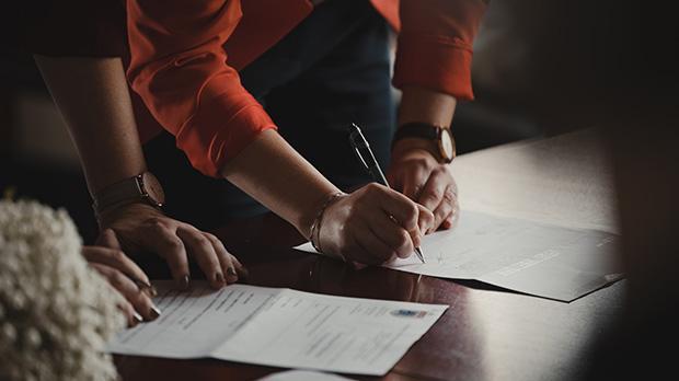 Person signing a contract on table
