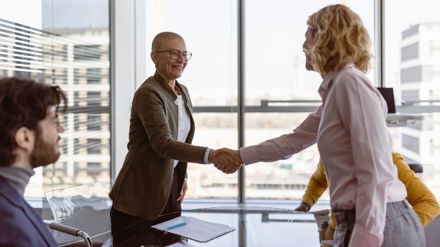 two business people shake hands in a board room