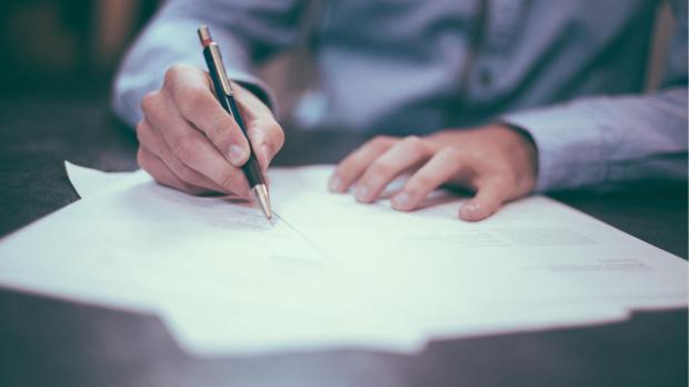 person in suit shirt writing on paper