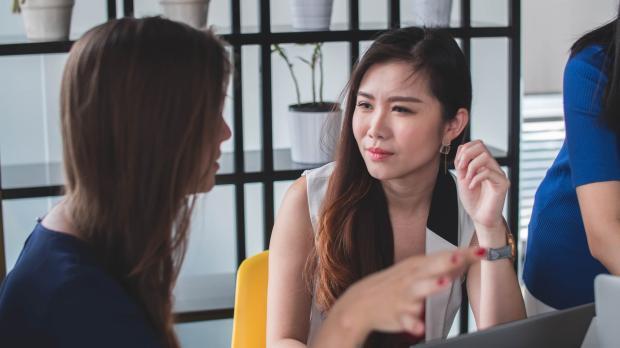Young women discussing work over a laptop