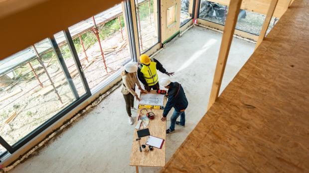Group in hard hats looking at plans in timber framed property