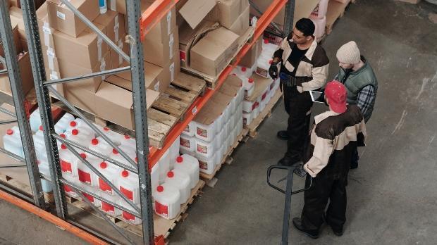 personnel in a warehouse looking at shelved products