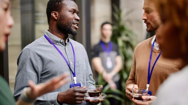 Employee drinking black coffee while standing with colleagues
