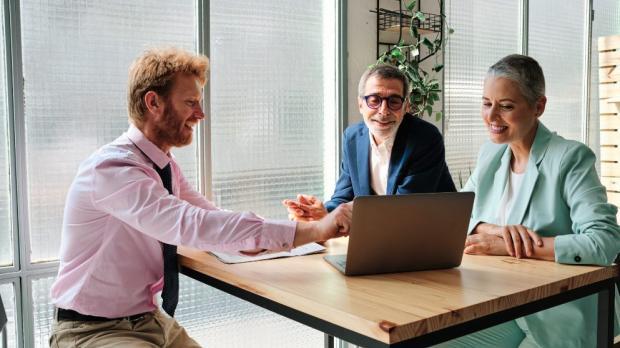 Three people sat at a table focused on a laptop