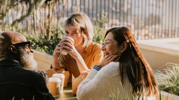 Group sat at a bench chatting in the sunlight