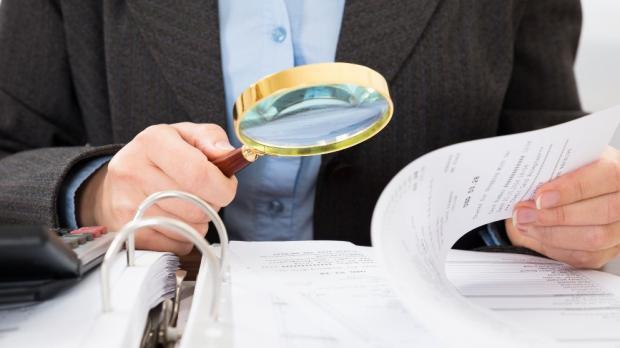 man with magnifying glass looking at documents