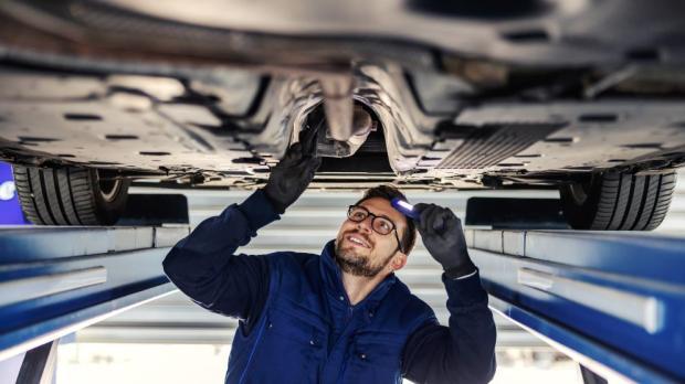 mechanic inspecting the underside of a car