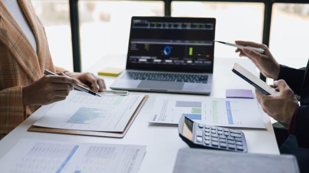 two personnel meet over a laptop showing data
