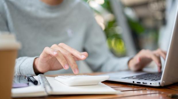 woman uses calculator and laptop