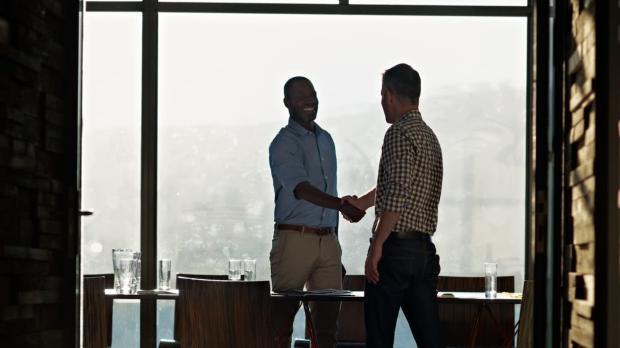 2 businessmen shaking hands in light filled office