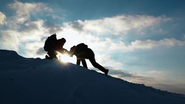 Travelers climb together up mountain. 