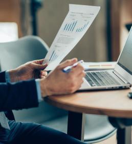 A financial accountant reviews a page of figures while using his laptop