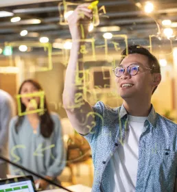 Engineer working out a problem by drawing a diagram on perspex screen