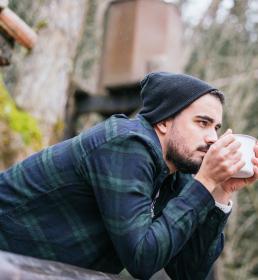 Man drinking coffee on the cottage terrace, melancholic autumn mood