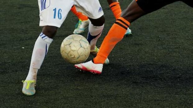 footballers tackling and kicking a ball 