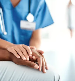 A nurse holds the hand of a patient