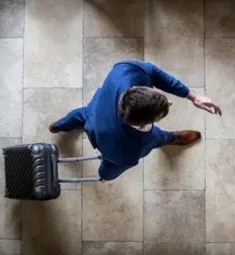 Man with suitcase aerial shot airport - Group Travel & Expat Insurance - Howden Belgium