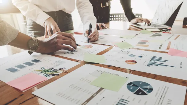 A group of finance professionals examine charts of figures