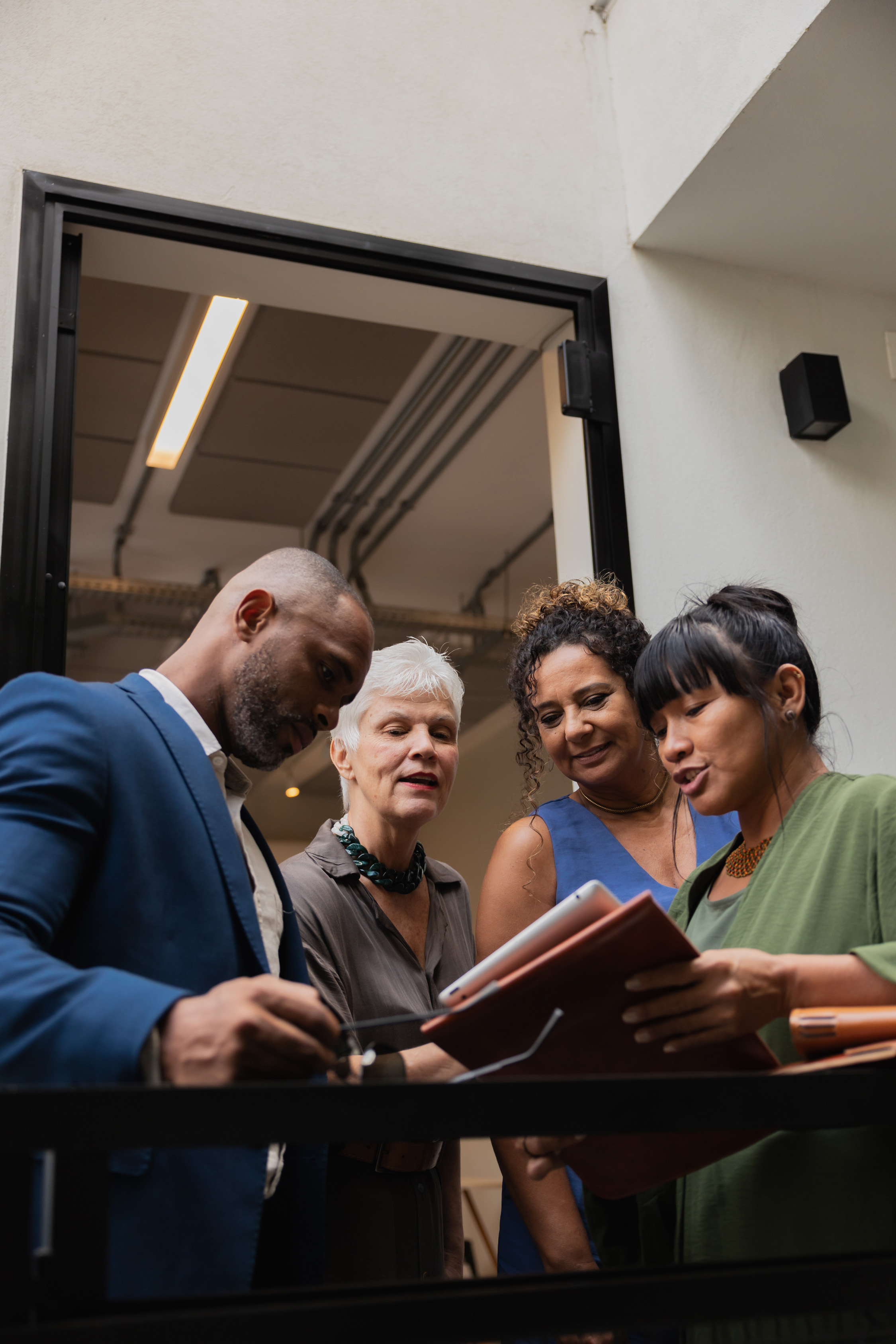 Group of four professionals collaborating over paperwork outside a contemporary office space